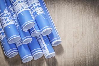 Blue rolled engineering drawings on wooden board directly above construction concept