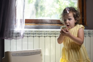 Little girl in a dusty room. Air purifier and coughing kid. Dust in the air. Allergy concept