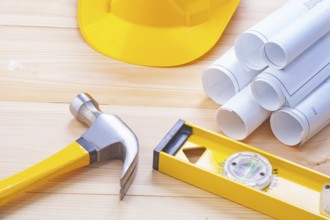 Claw hammer rolled blueprints construction level hardhat on wooden boards horizontal version