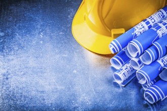 Blue blueprints hard hat on metallic background construction concept