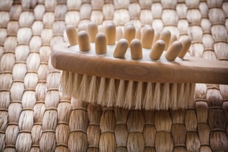 Close up image of wooden massager with scrubbing brush on wicker background healthcare concept