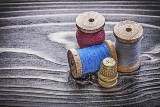 Vintage reels of thread thimbles on wooden board handicraft concept