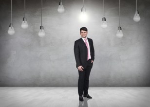 Businessman stands in a gray room with hanging bulbs