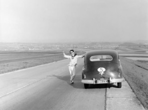 Vaction in Italy in the 1951. A man at his car during a car vacation trip in Italy. He has stopped