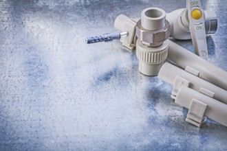 Plastic water pipe valve clamps connectors on metallic background construction concept