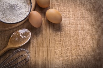 Organized copyspace eggs flour in bowl spoon corolla on wooden board food and drink concept