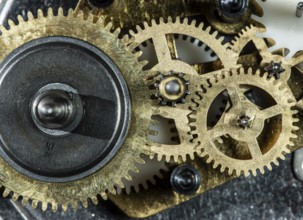 Close up metal gears mechanism. Golden colours. Hard light. Clock interior mechanism parts
