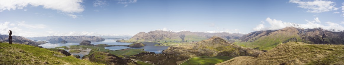 View over a wide mountain landscape with lakes and green terrain under a clear sky, Wanaka, New
