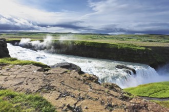Iceland. Grand Gullfoss. In mid-July, bubbling water illuminated by a bright morning sun