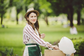 Photo theme small business cooking sweets. A young caucasian woman with an apron trader in the hat