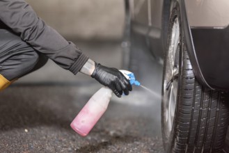 Professional car washer cleaning car alloy wheels