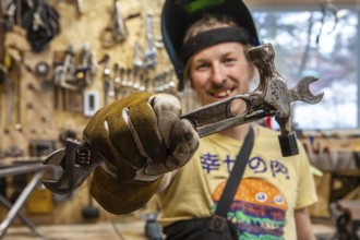 A front portrait view of a skilled tradesman showing his handmade multi-tool, consisting of a