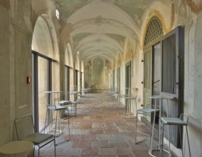 Modern bistro seating in a historic arcade with fresco paintings, successful combination of