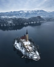 Aerial shot of lake Bled on a calm winter morning with snow