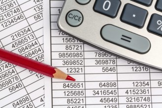 A calculator lies on the figures of a balance sheet and statistics. Symbol photo for turnover,