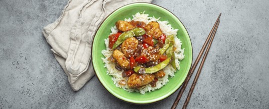 Asian sweet and sour sticky chicken with vegetables stir-fry and rice in ceramic bowl with