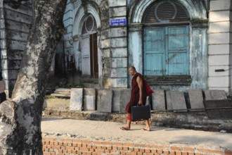07.10.2013, Yangon, Myanmar, Asia, A Buddhist monk walks with his briefcase past an old colonial
