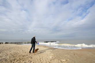 Man with dog at the beach in Dutch Zeeland