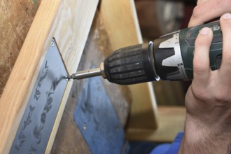 Craftsman working on wood with a drill - close-up carpenter