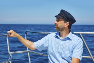 Beard sailor man sailing sea ocean in a boat with captain cap looking horizon