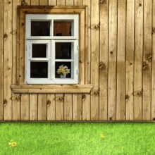 Exterior of wooden house with window and green grass in the yard