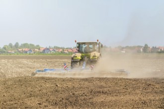 Farmer in tractor preparing land seedbed cultivator. Agriculture tractor landscape