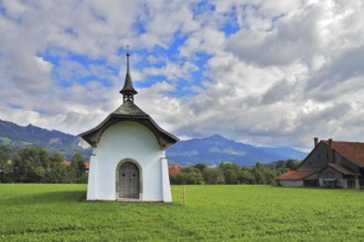 Small rural chapel on a green meadow. Picturesque forged door decorated rows of round rivets. A