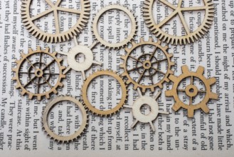 Wooden cogwheels on a page of a book. Industry concept information