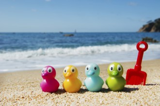Colorful toy ducks in the sand at the beach