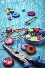 Coil, beads and tools for needlework on turquoise wooden background