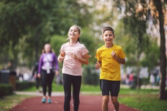 Sports and fitness in adolescence. Caucasian twins boy and girl run on the jogging track in the