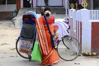 Kanchipuram, Tamil Nadu, South India, A traditionally dressed woman carries colourful fabrics on a