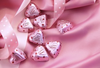Valentine's chocolate hearts on pink satin with ribbon