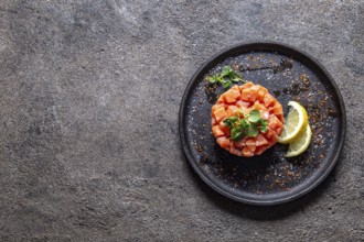 Food, Raw salmon, avocado purple onion salad served in culinary ring on black plate. Black concrete