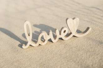 Wooden word love on sandy beach background. Concept of romantic holiday anniversary, proposal,