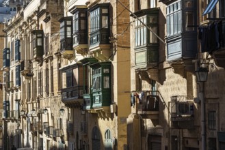Valletta, Malta, 01 07 2022: Historical houses with wooden bow windows and terraces in a narrow
