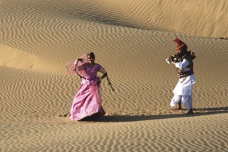 Rajasthani man playing been in front of woman in sand dune, Rajasthan, India MR#704C, 704D