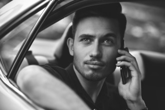 Handsome man sit in the back seat of the car and use a phone