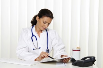 Young doctor in her medical practice at her desk Austria
