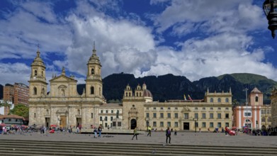 A historic cathedral and buildings surround a bustling plaza with people walking under a dramatic