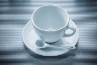 Coffee cup saucer teaspoon on striped background