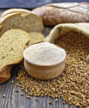 Buckwheat flour in a wooden bowl, buckwheat in the bag, the bread slices on a wooden boards