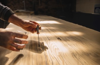 Person using tools on wood in a workshop with warm sunlight creating a focused and serene