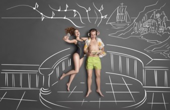 Love story concept of a romantic couple on the shore against chalk drawings background, view from