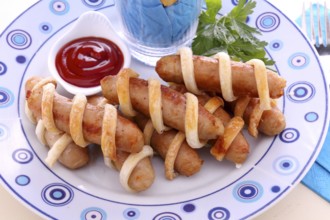 Twisted pastry around chicken sausages with ketchup