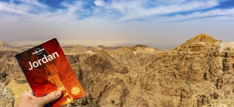 Lonely Planet travel guide against dramatic Jordan mountains and sky to promote travel and tourism