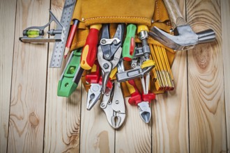 Set of construction tools in toolbelt on wood boards close up
