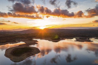 Drone aerial view of a lake reservoir of a dam with perfect reflection on the water of the sunset
