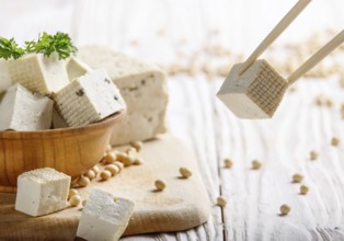 Soy Bean curd tofu in wooden bowl on white wooden kitchen table. Non-dairy alternative substitute