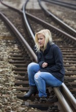 A young woman is sad, anxious and depressed. Sits on a railway track and is lonely